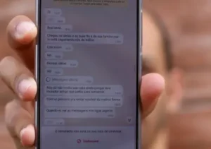 Mulher segurando um celular mostrando mensagens de ameaça de um golpista.