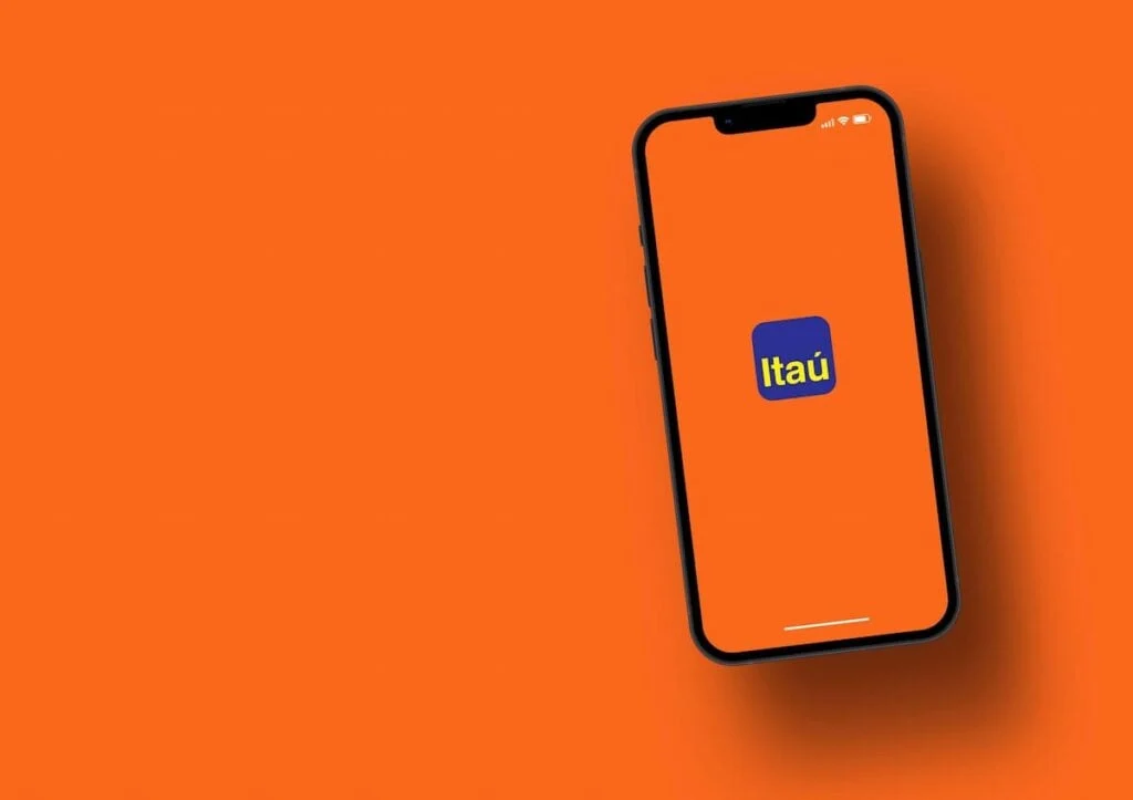 Celular com tela exibindo o logo do banco Itaú em destaque sobre fundo laranja, com o aparelho na diagonal e bordas pretas, em imagem estilo fundo para propaganda.